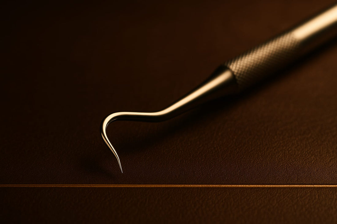 Dental explorer probe with shepherd’s hook tip in dramatic macro on espresso leather