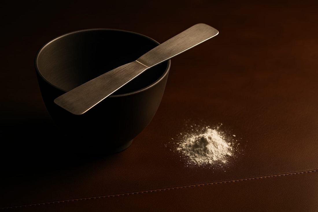 Black rubber mixing bowl with a stainless plaster spatula across its rim